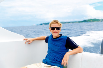 Fototapeta na wymiar Happy teen boy in sunglasses on the yacht. Tropical sea 