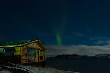 Aurora and a small wooden house near the sea