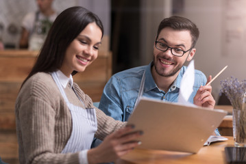 Delighted couple smiling and looking at folder.