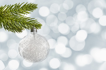 White christmas ball hanging from a branch, bokeh background
