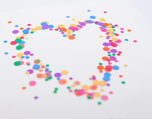 Heart symbol made of colorful confetti on white background