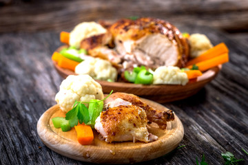 Whole roasted chicken with vegetables on wooden background