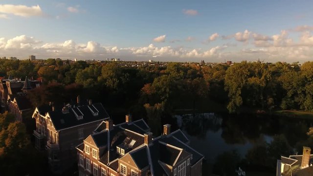 Aerial flying over expensive houses and park during golden hour in Amsterdam. Camera  rises to reveal greater Amsterdam.