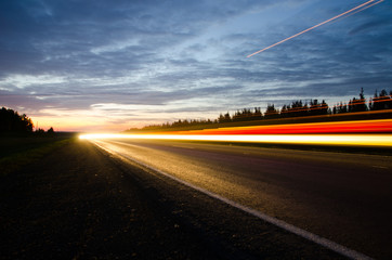 Rural road in twilight with the headlights of passing cars on it