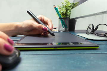 Hand of graphic designer working with stilus and tablet
