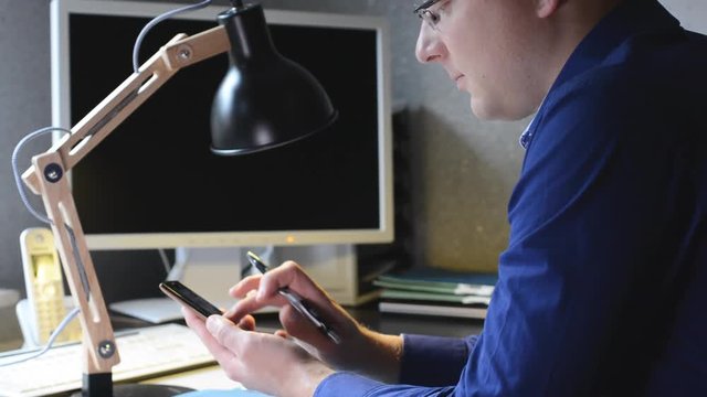 Mann schreibt eine Nachricht mit seinem Handy im Homeoffice