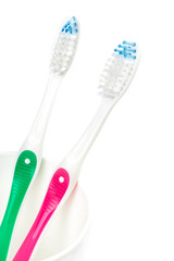 Toothbrushes in glass on table on light background