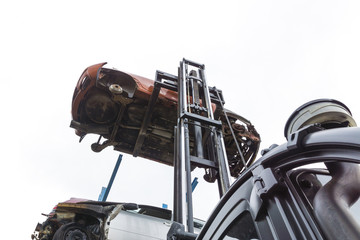 forklift hoisting car wrecks at the junkyard
