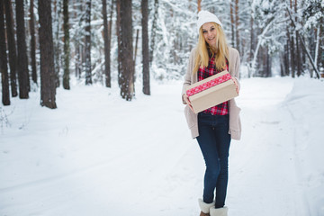 Fototapeta na wymiar girl holding a Christmas gift in winter forest