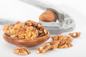 Cracking walnuts with nutcracker over white background. Walnut kernels.