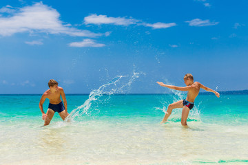 Happy teen boys having fun on the tropical beach. Summer vacatio