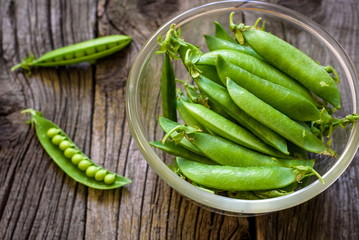 Green pea in bowl of top view on rustic wooden background with c