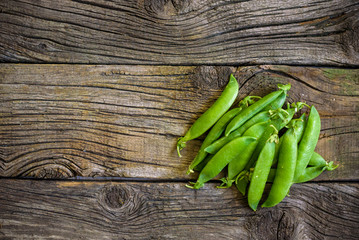 fresh green peas over a natural wood table, placed in  nice way