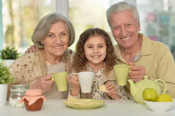 grandparents with granddaughter drinking tea 