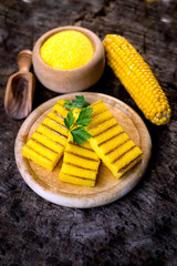 Grilled polenta on old wooden background