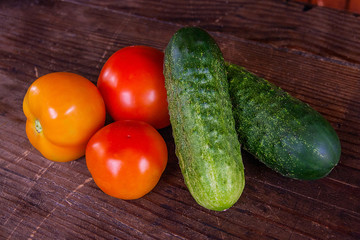 Close up view of fresh, ripe tomatoes and cucumbers on wood back