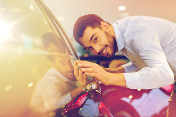 happy man touching car in auto show or salon