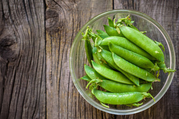 Fresh, young unpeeled green peas in a glass plate