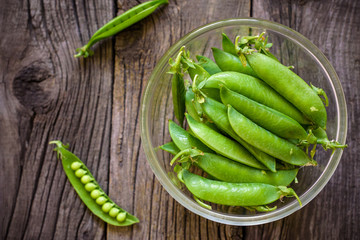Fresh, young unpeeled green peas in a glass plate