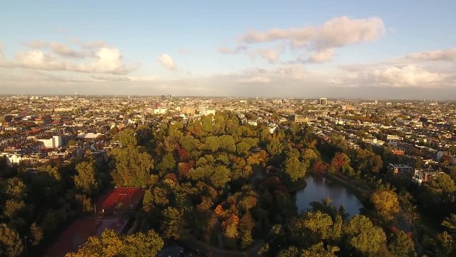 Aerial flying over Vondelpark in Amsterdam, with a great view over the city at golden hour.