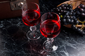 Glass of red wine on dark marble background. Cluster of blue gra