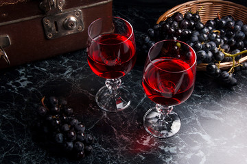 Glass of red wine on dark marble background. Cluster of blue gra
