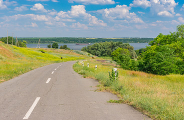 Fototapeta na wymiar Summer landscape with rural road and meadow at the roadside near Dnepr river, Ukraine.