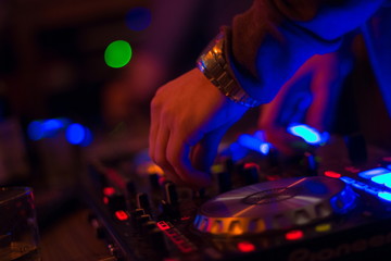 Naklejka premium DJ turntable console mixer controlling with two hand in concert nightclub stage.