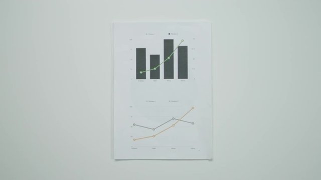 Male hands putting graphic charts and a pen on a table