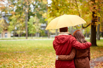 happy couple with umbrella walking in autumn park