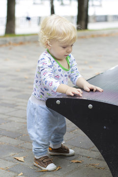 A small child learns to walk near the benches, toddler