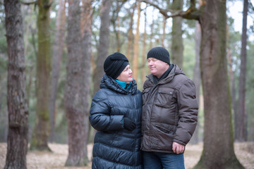 Old couple walking in the forest. Having a good time together. Smiling and talking on autumn or spring