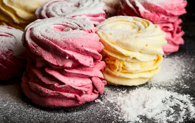 Rows of colorful meringues on a black wooden background