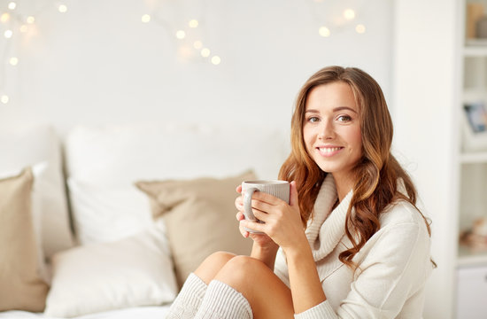 happy woman with cup of coffee in bed at home