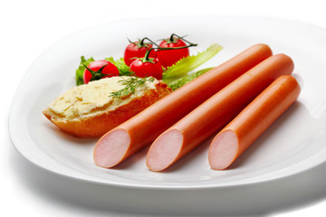 Three sausages on white plate with white bread with butter and