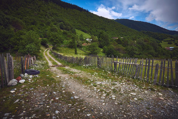 Fototapeta na wymiar Грунтовая дорога вдоль забора в горной деревне в Сванетии, Грузия