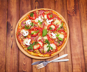 Pizza, knife and fork against dark wood.