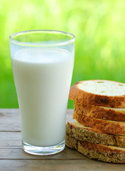 Bread cut pieces  with milk glass on wooden table,green blurred