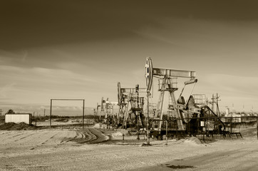 Group of oil pumps and wellheads in the oilfield during winter. Oil and gas concept. Toned. 