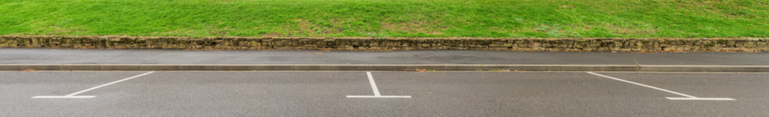Obraz premium Hintergrund als Panorama zwei leere Parkplätze am Staßenrand mit Gehweg und Gras - Background as a panorama two empty parking places on the roadside with walkway and grass