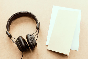 Headphone with brown and white paper note on wood desk in music studio.