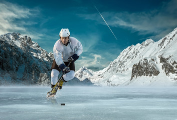 Fototapeta premium Ice hockey player in action outdoor around mountains