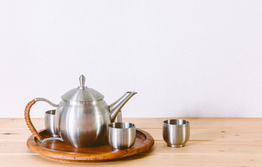 Teapot with cup of tea on wooden table