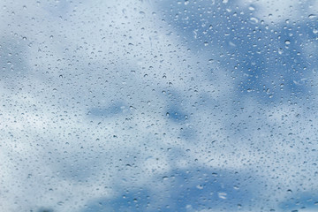 Raindrops on glass and blurred blue sky