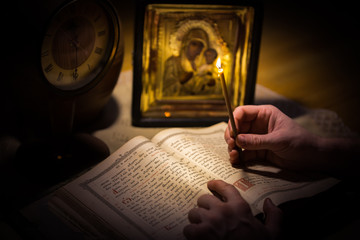 А man with a candle reading an antique bible