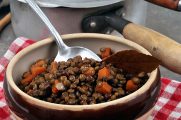 Bol de lentilles et de dés de carottes dans un bol près d'une casserole