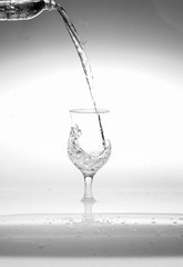 Glass of water with water splashes and wet
