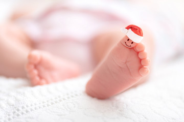 A close-up of tiny baby feet with Santa Claus hat