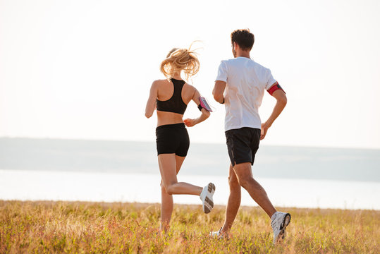 Back view of young fitness man and woman doing jogging