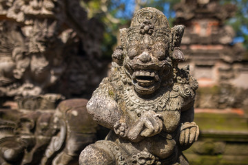 Traditional guard demon statue carved in dark stone on Bali isla
